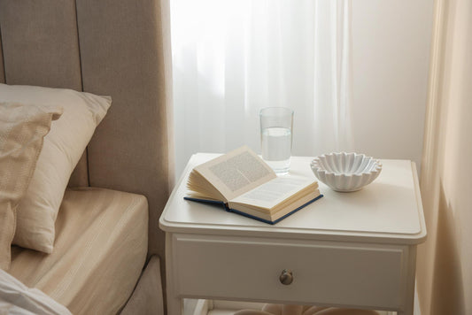 quiet bedside scene with a book, soft linens and warm lighting, in DIDO's muted blush, cream and burgundy palette